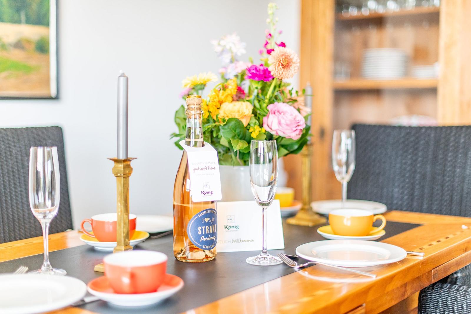 Set dining table with flowers, glasses, and a bottle of sparkling wine.