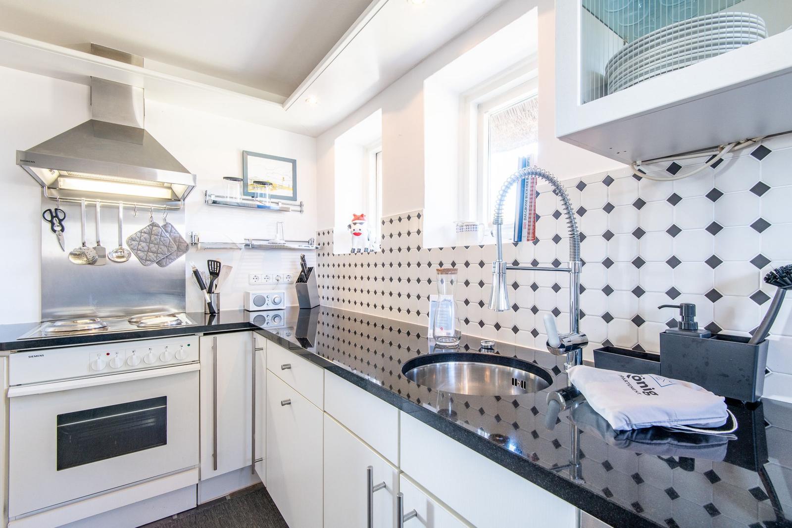 Kitchen with white cabinets, black countertop, and patterned tile backsplash