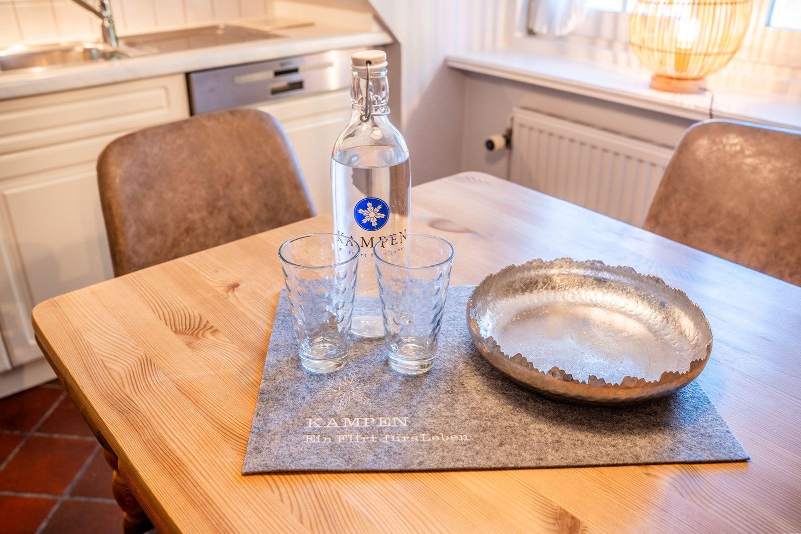 Nachhaltigkeit beginnt oft bei kleinen Dingen – wie dieser stilvollen Glasflasche mit Kampen-Logo, die Sie in Ihrer Ferienwohnung erwartet.