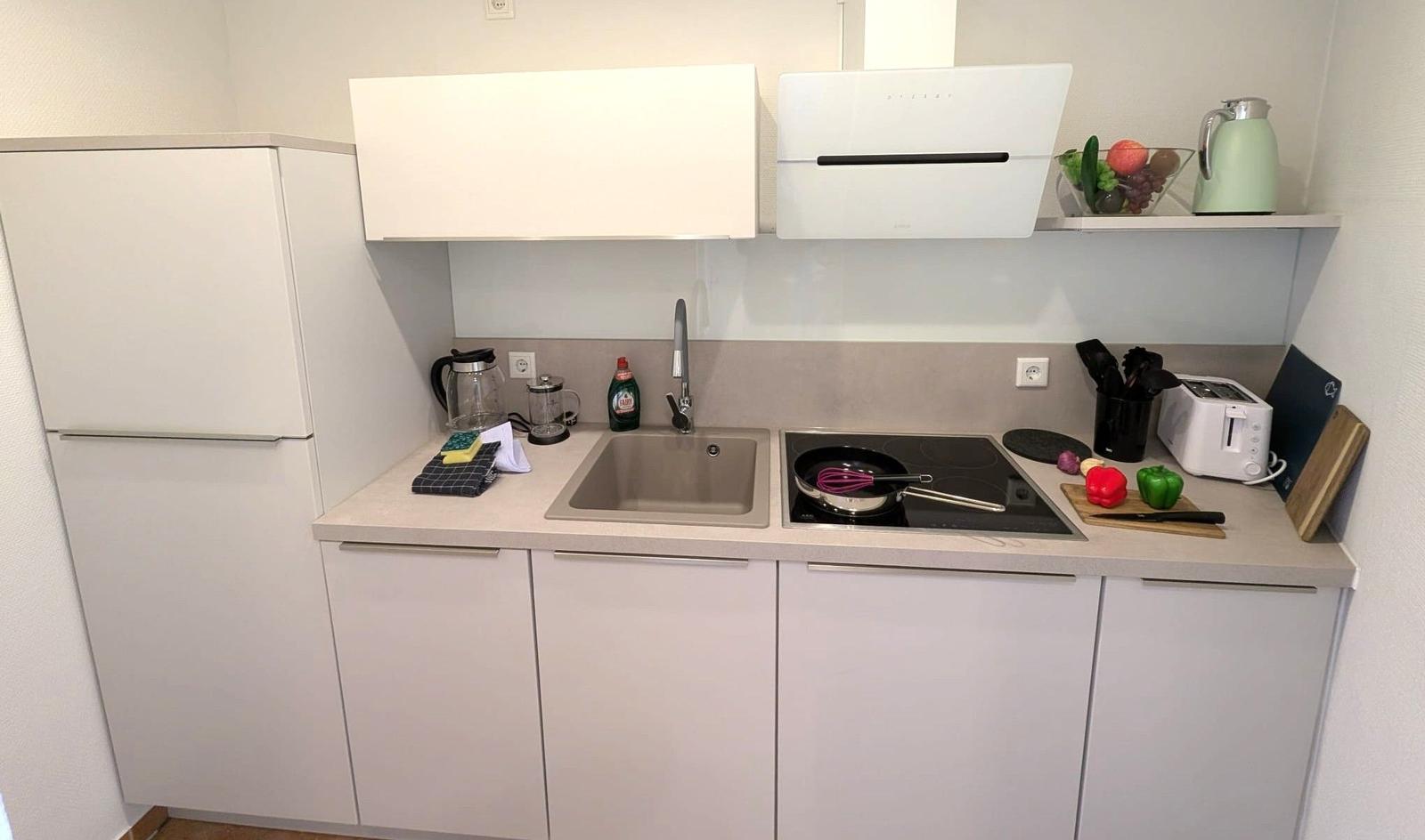 Küche mit Arbeitsplatte, Spüle, Herd und Kühlschrank.
