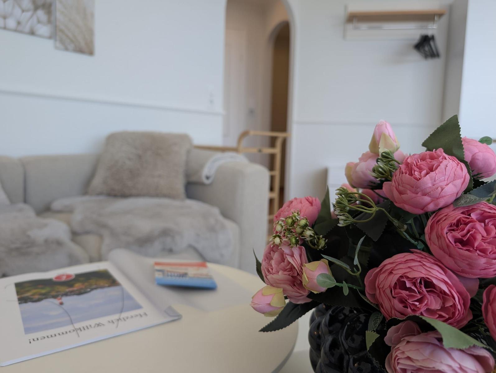 Ein Wohnzimmer mit einem Sofa, einem Tisch und einer Blumenvase.