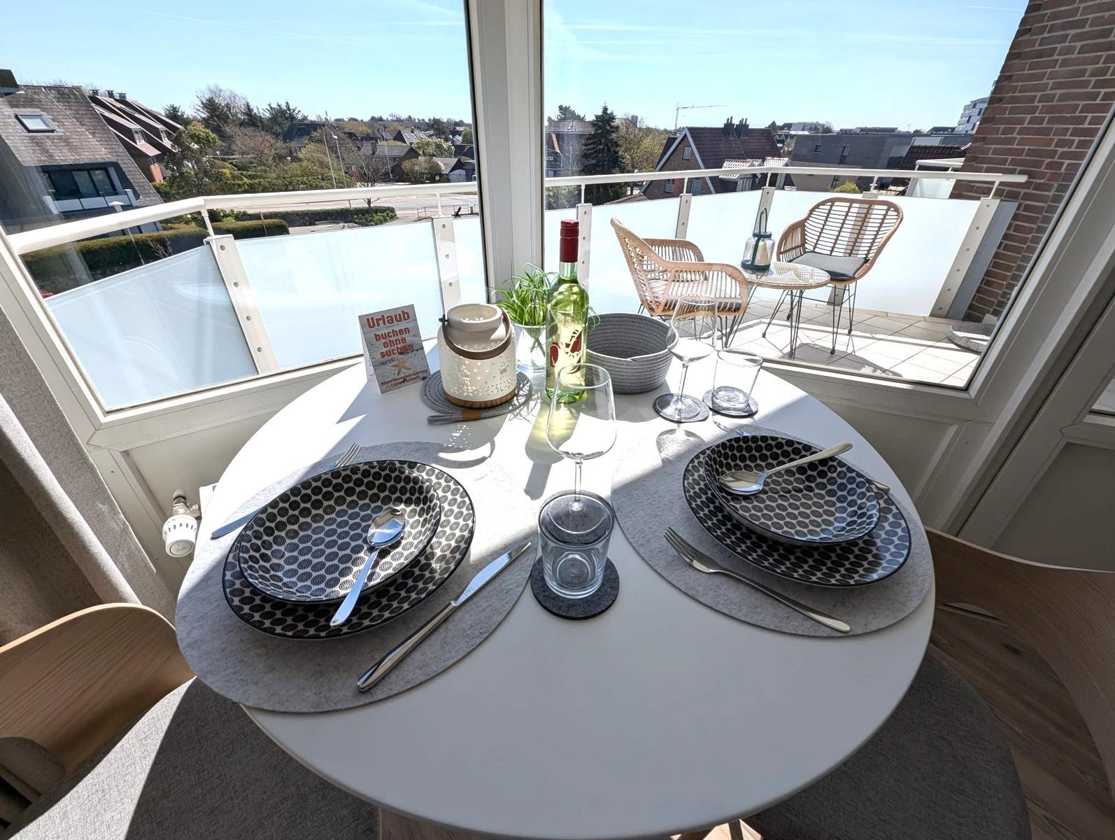 Runder Tisch mit Platz für zwei, Blick auf Balkon mit Sitzgelegenheiten.