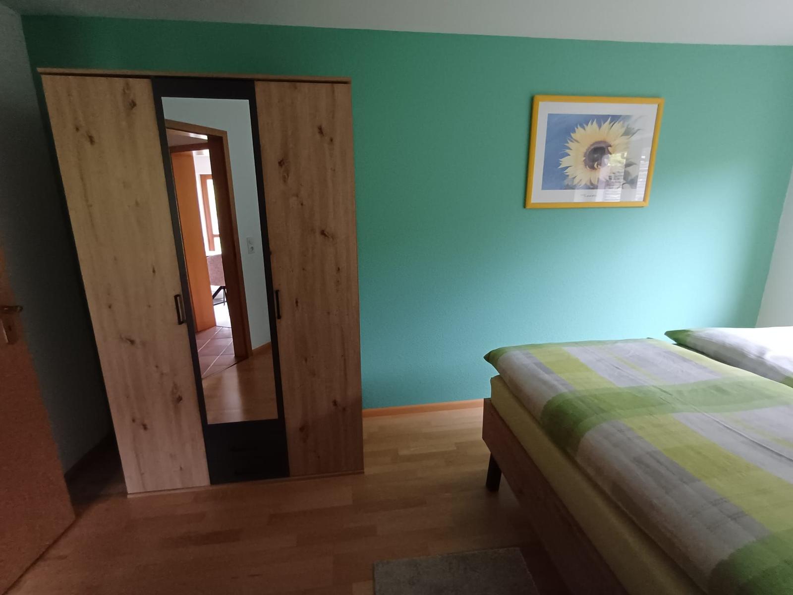 Schlafzimmer mit Bett, Kleiderschrank und Wandbild.