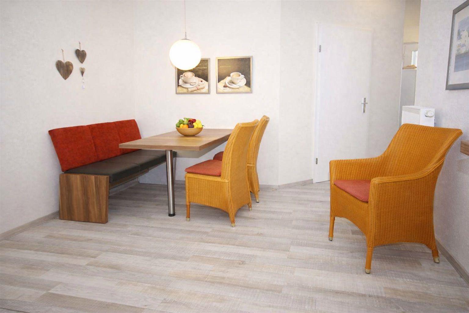 Essbereich mit Tisch, Sitzbank und Stühlen. Wandbild und Lampe sind sichtbar.