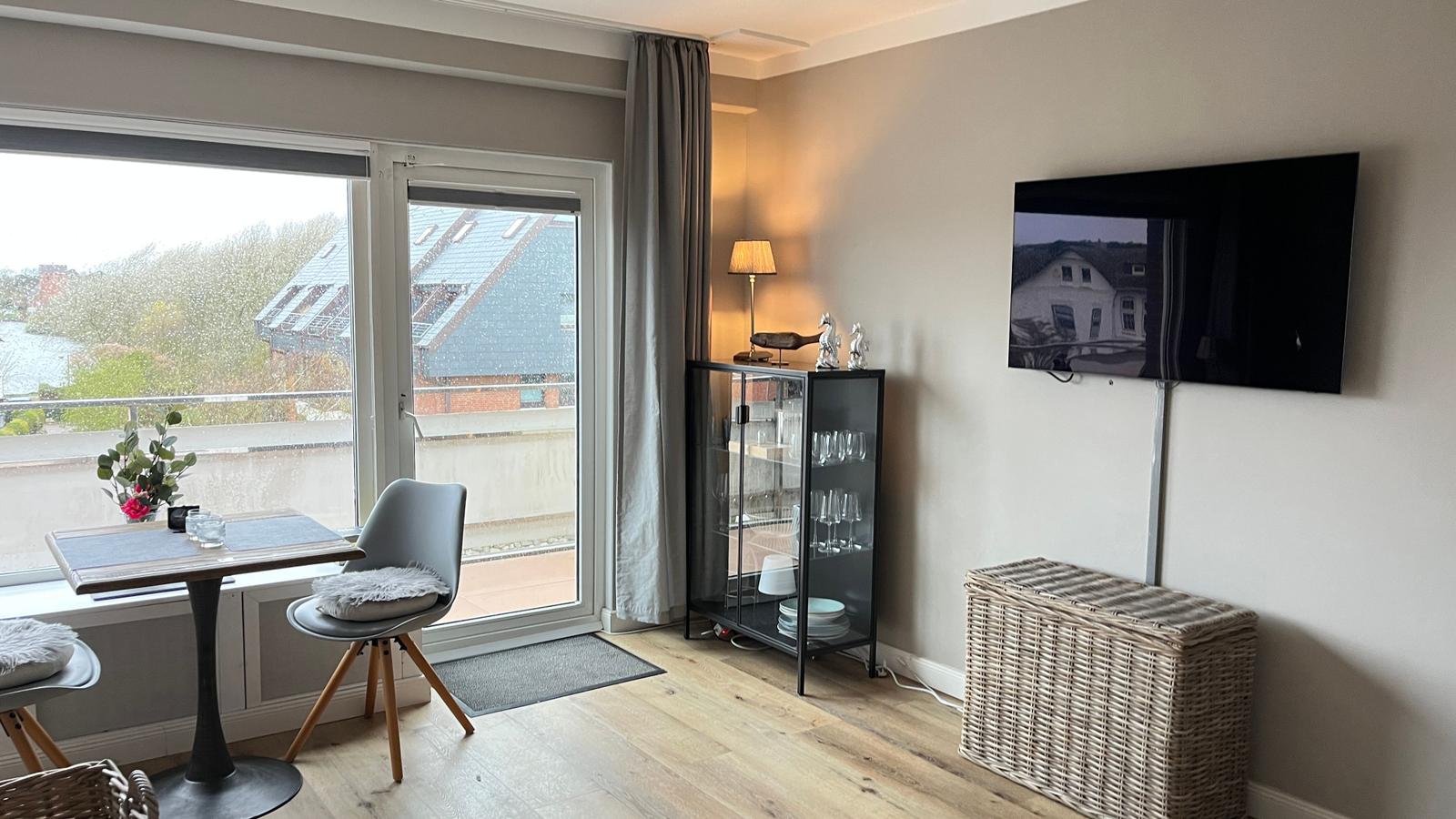 Wohnbereich mit TV, Glasvitrine und Balkonansicht