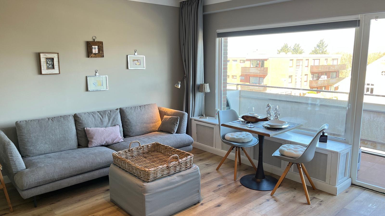 Wohnzimmer mit Sofa, Esstisch und Balkonansicht.