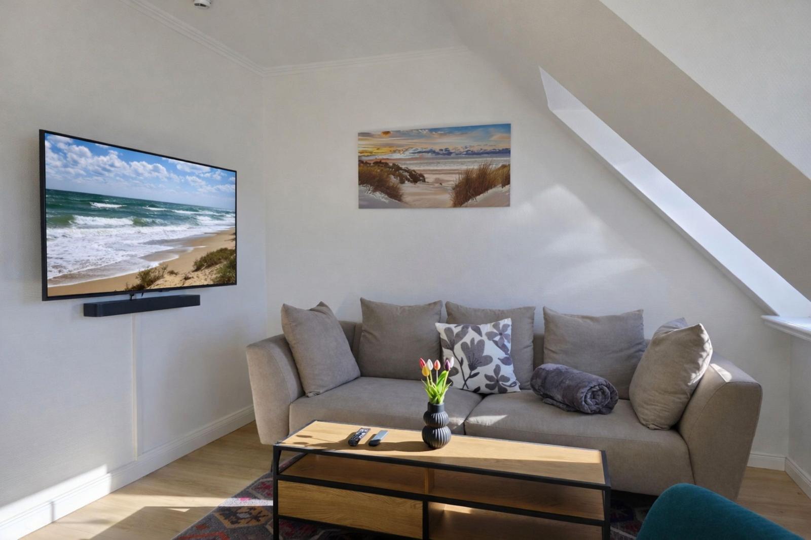 Wohnzimmer mit Sofa, Fernseher und Wandbild.