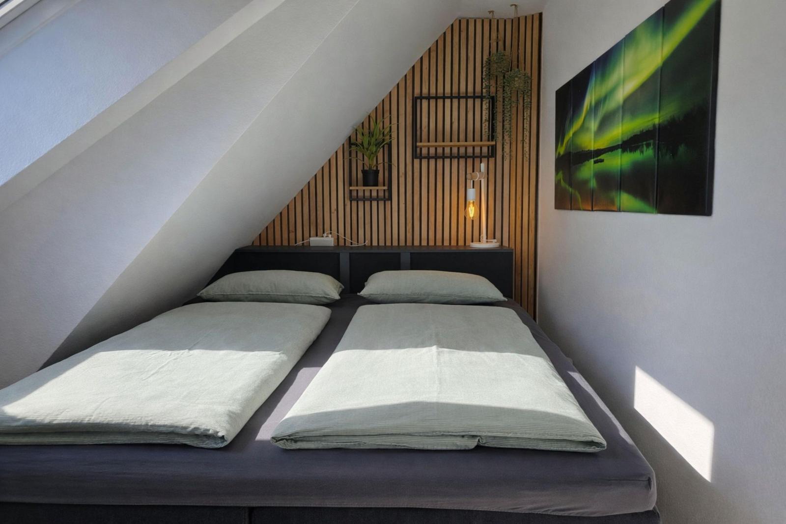 Schlafzimmer mit Doppelbett, Holzwand und Wandbild