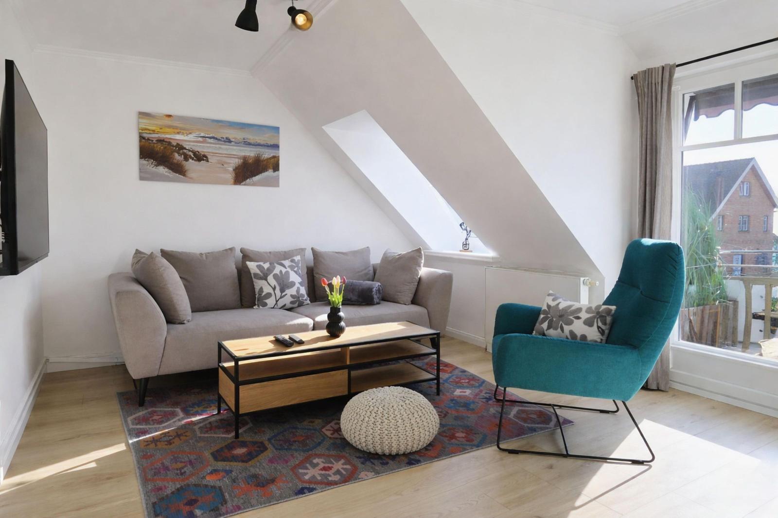 Wohnzimmer mit Sofa, Sessel und Fenster. Decke geneigt. Teppich und Couchtisch.