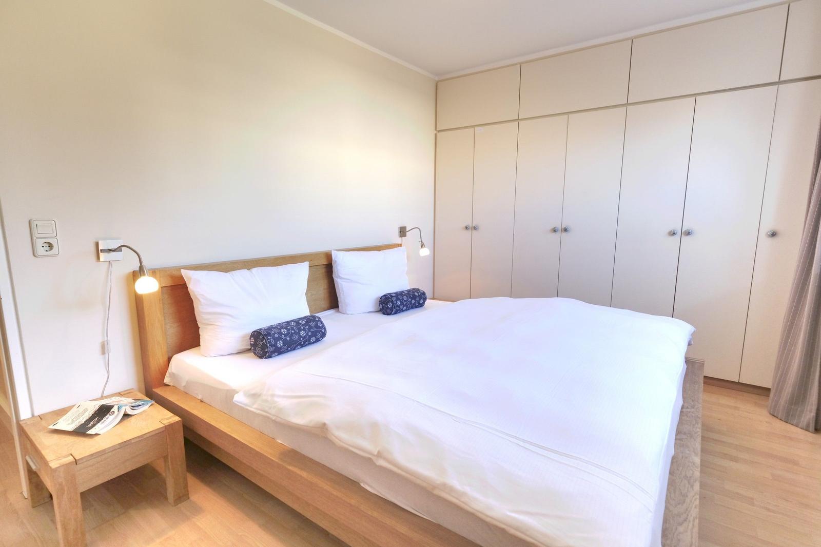 Bedroom with double bed, wooden frame, nightstand, and wardrobe.