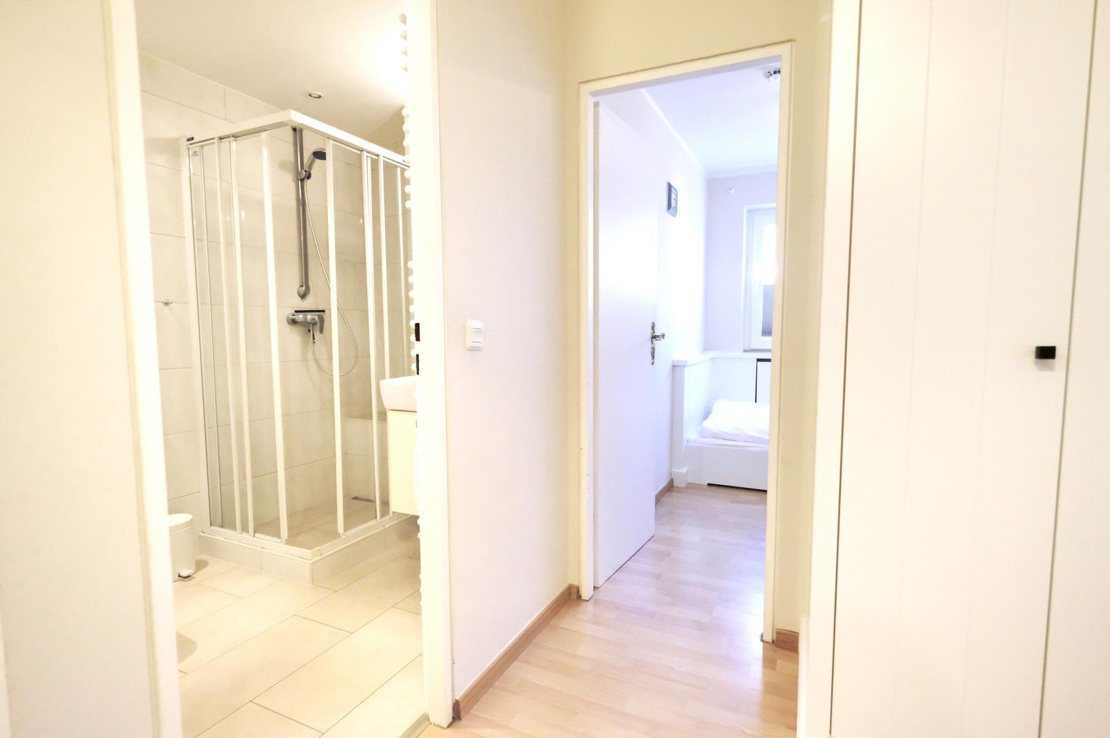 Bathroom with shower and bedroom with bed visible.
