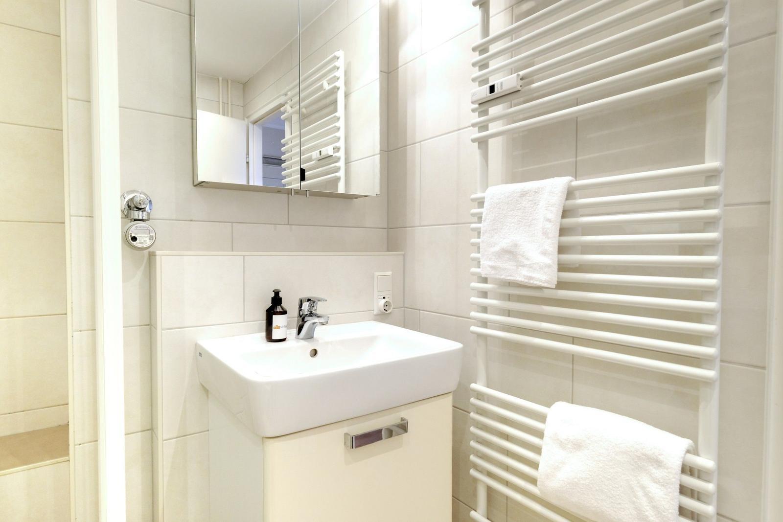 Bathroom with sink, mirror, and heated towel rack with towels.