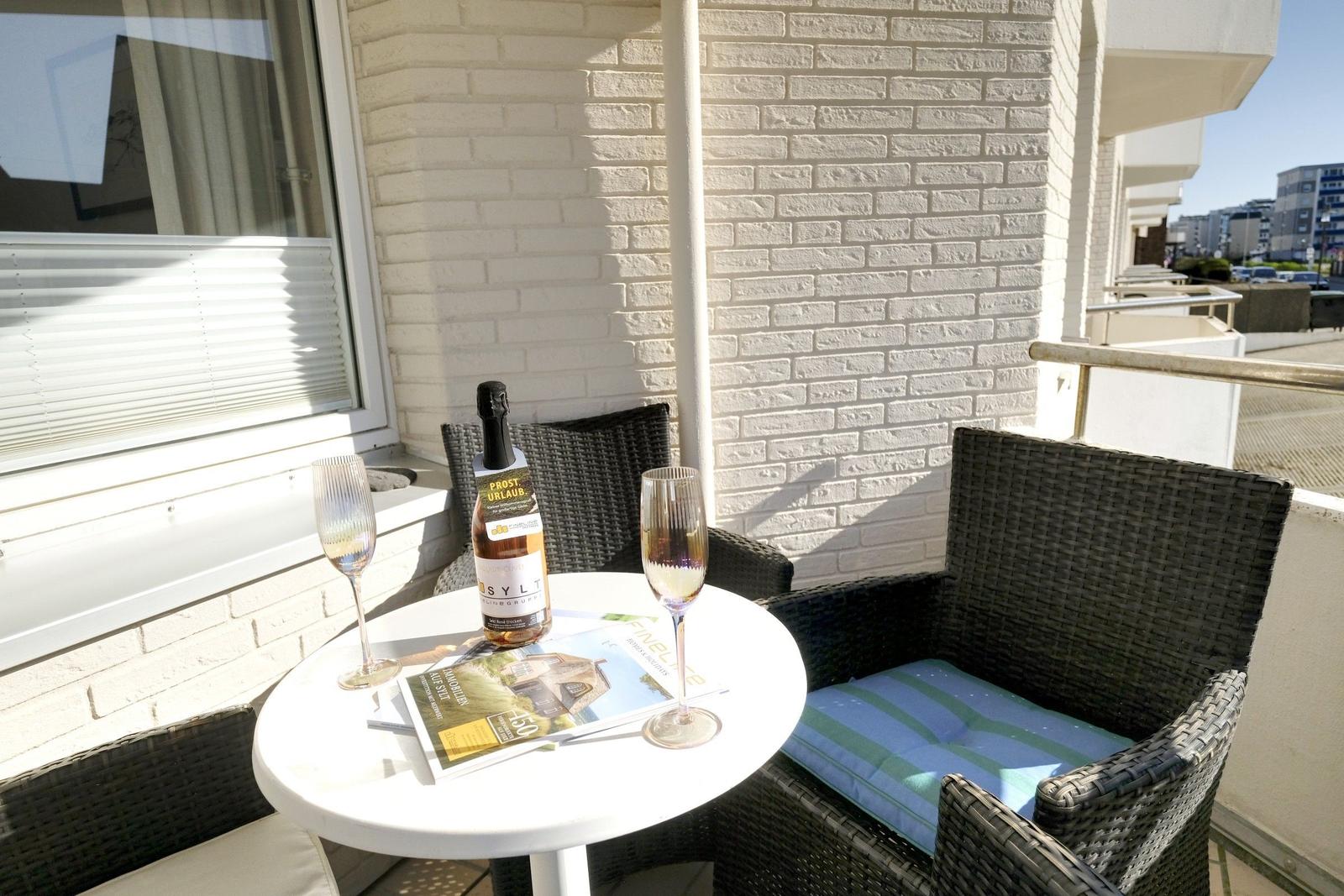 Terrace with table, two chairs, and a bottle of Sylt sparkling wine.