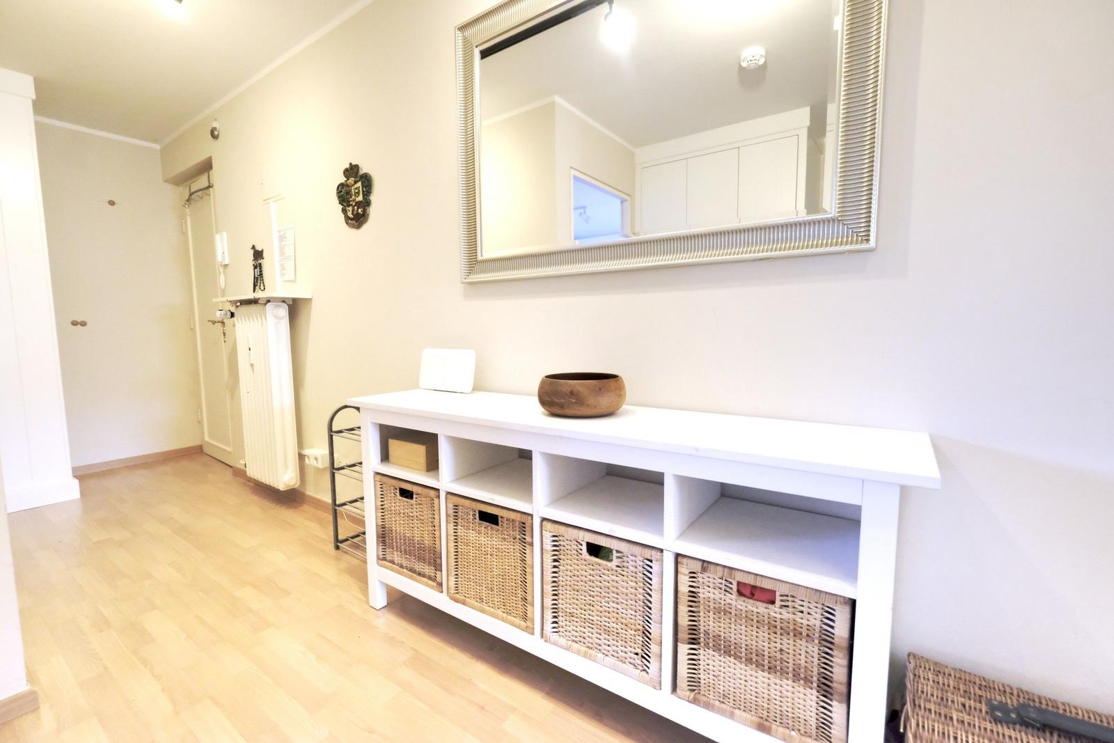 Entryway with white cabinets and baskets. Mirror on the wall.