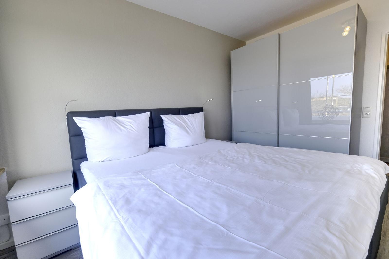 Schlafzimmer mit Doppelbett, Nachttisch und Kleiderschrank.