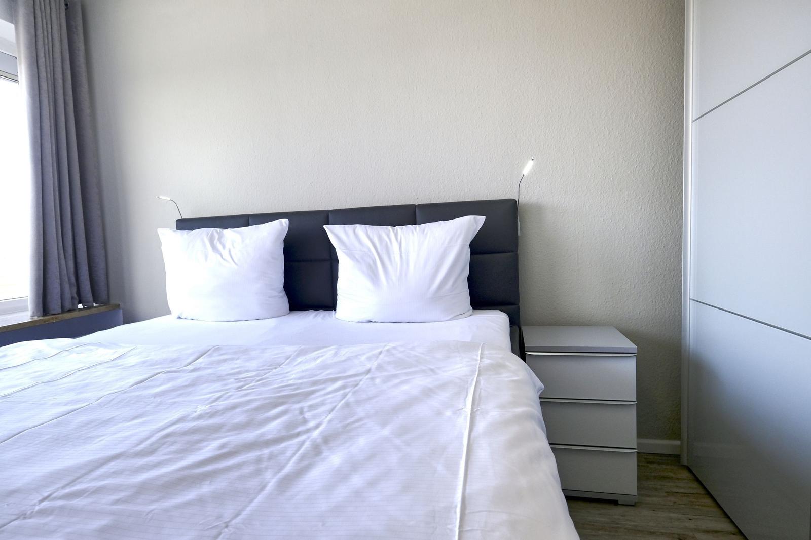 Schlafzimmer mit Bett, Nachttisch und Kleiderschrank.