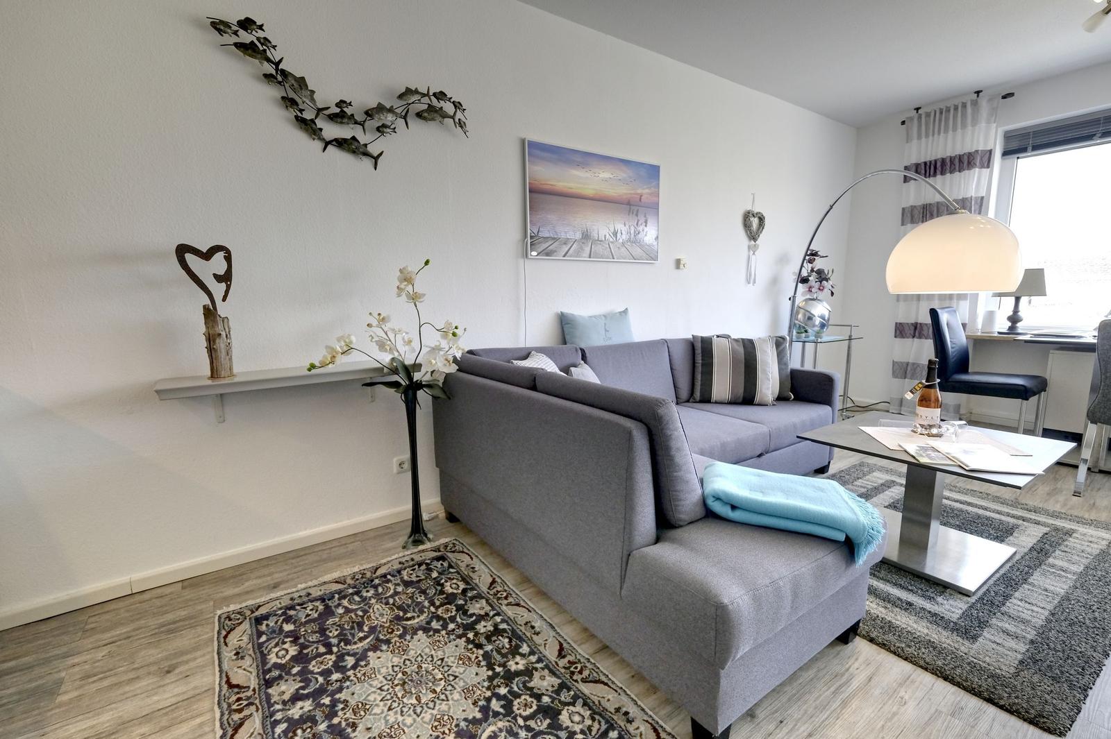 Ein Wohnzimmer mit grauem Sofa, Teppich und Wanddekoration.