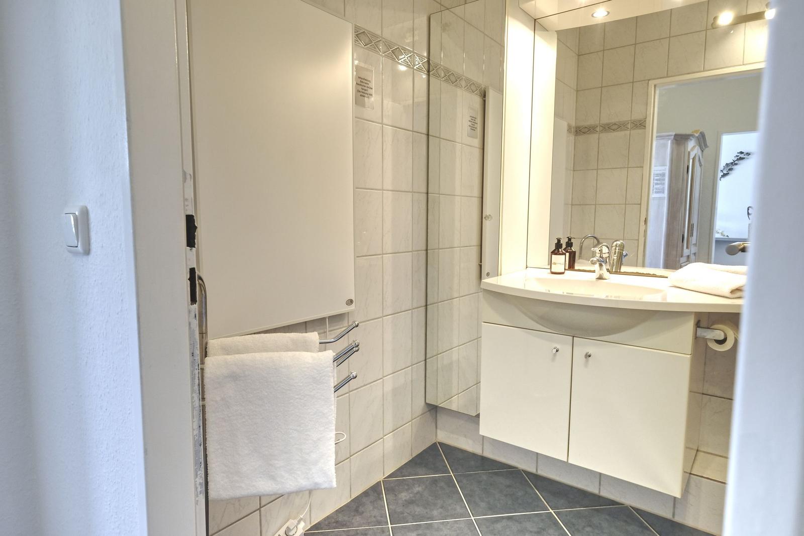 Badezimmer mit Waschbecken, Spiegel und Handtuchhalter.