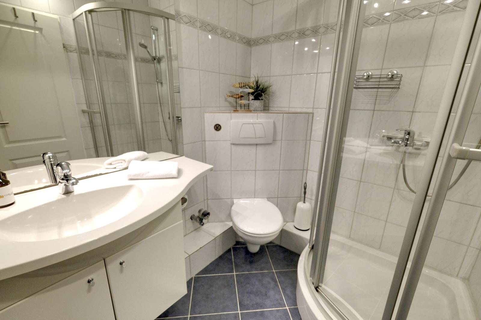 Badezimmer mit Dusche, Waschbecken und Toilette.