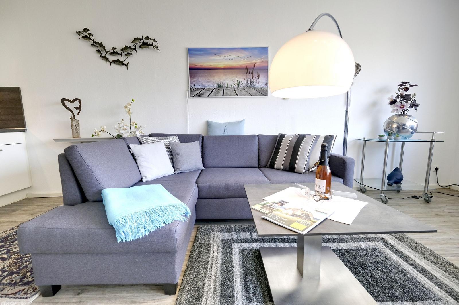 Ein Wohnzimmer mit grauem Sofa, Tisch und Teppich.