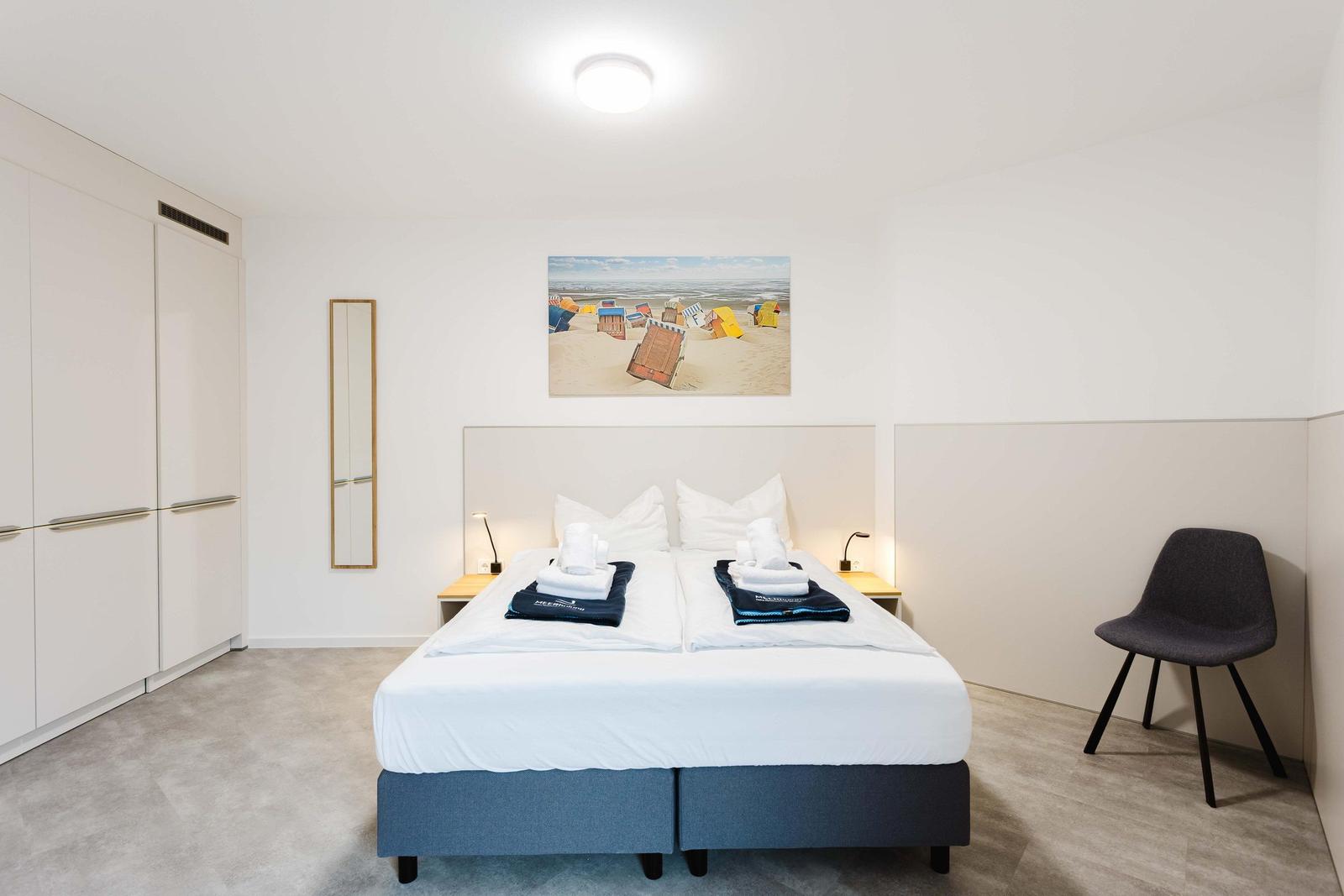 Schlafzimmer mit Doppelbett, Kleiderschrank und Wandbild.