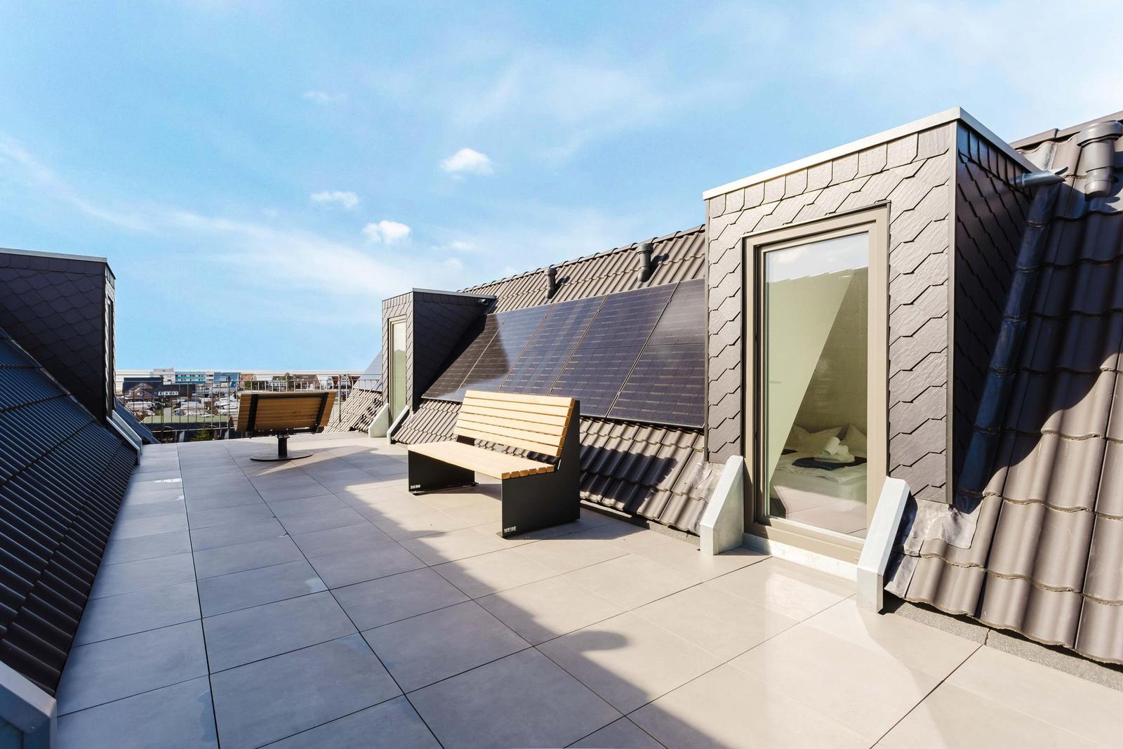 Terrasse mit Bank, Solarpaneelen und Blick auf die Stadt
