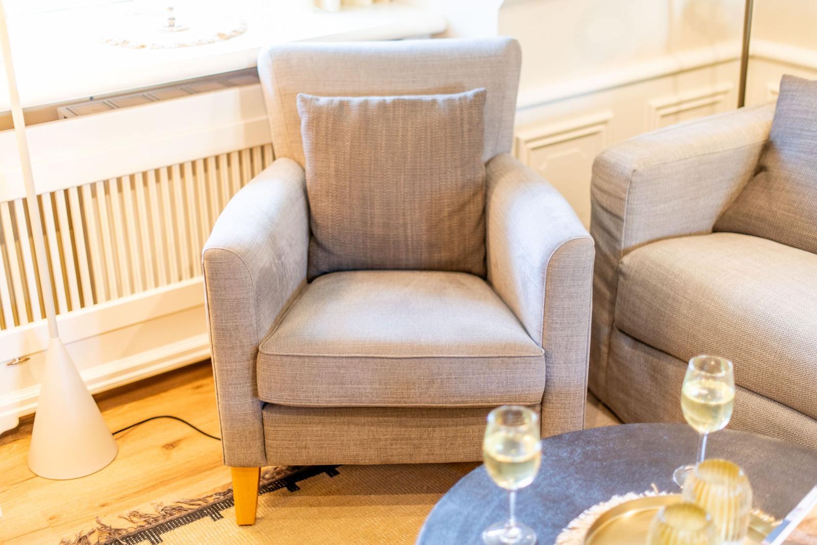 Ein bequemer Sessel mit Kissen steht neben einem Sofa.