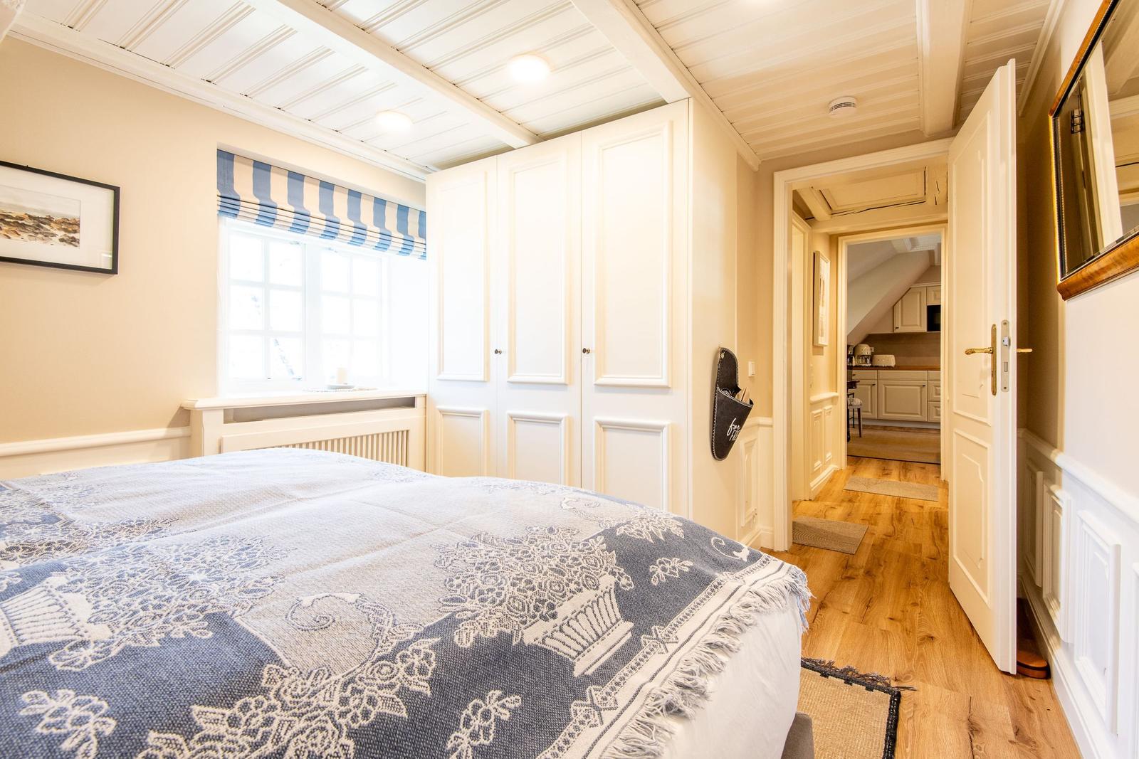 Schlafzimmer mit Bett, Fenster und Tür zum Flur