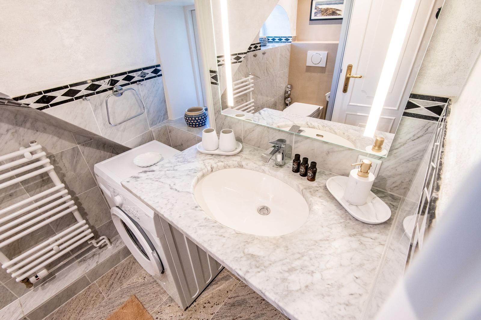 Badezimmer mit Waschmaschine, Waschtisch und Spiegel