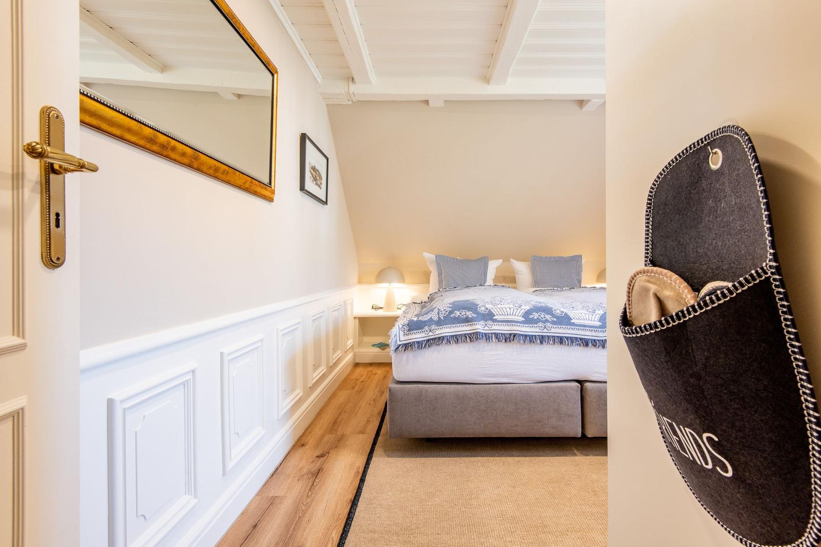 Schlafzimmer mit Bett, Spiegel und Holzboden