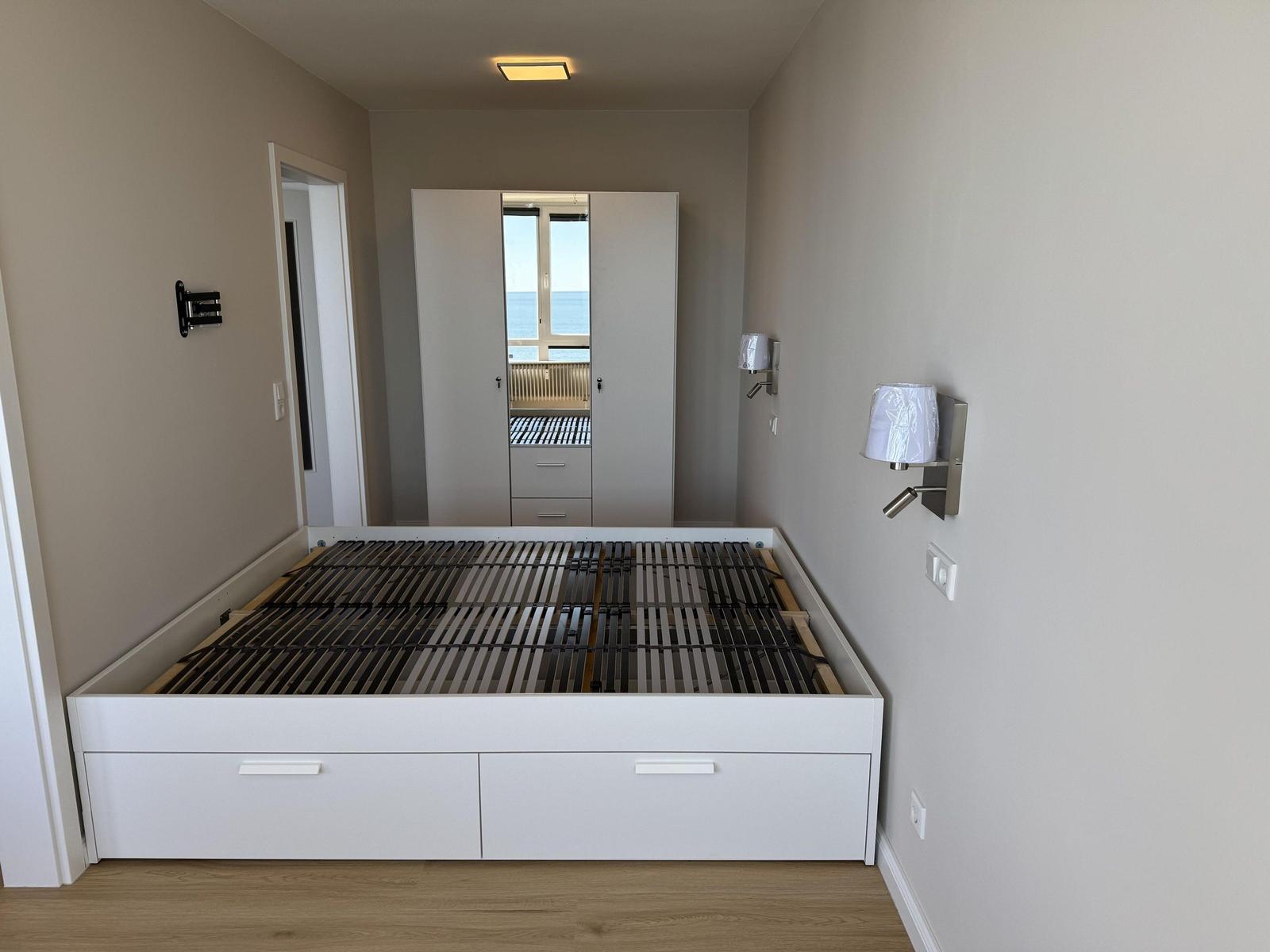 Bedroom with white bed frame and sea view.