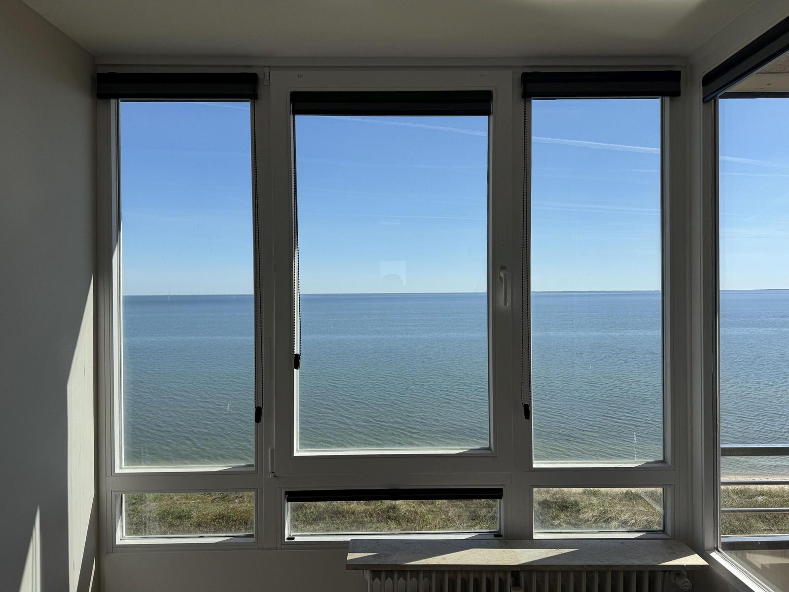 Large window with sea view. View of calm water under blue sky.