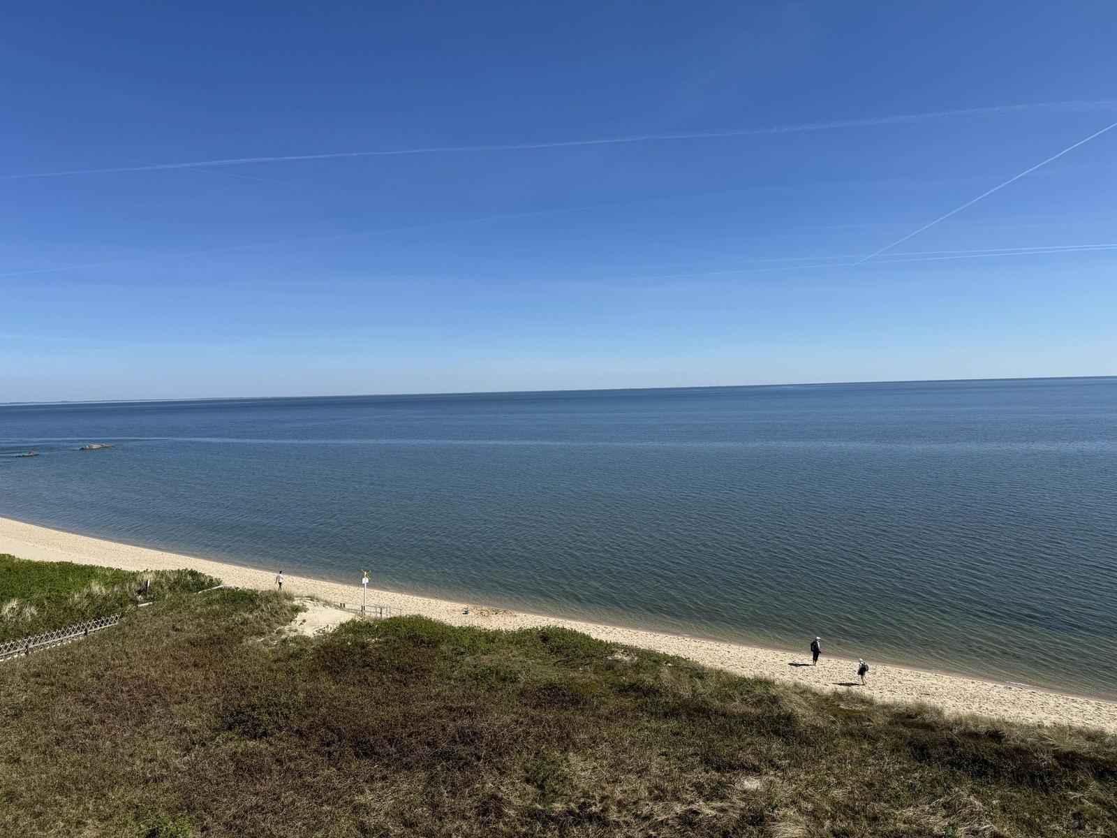 Beach with sand and sea under blue sky with few people.