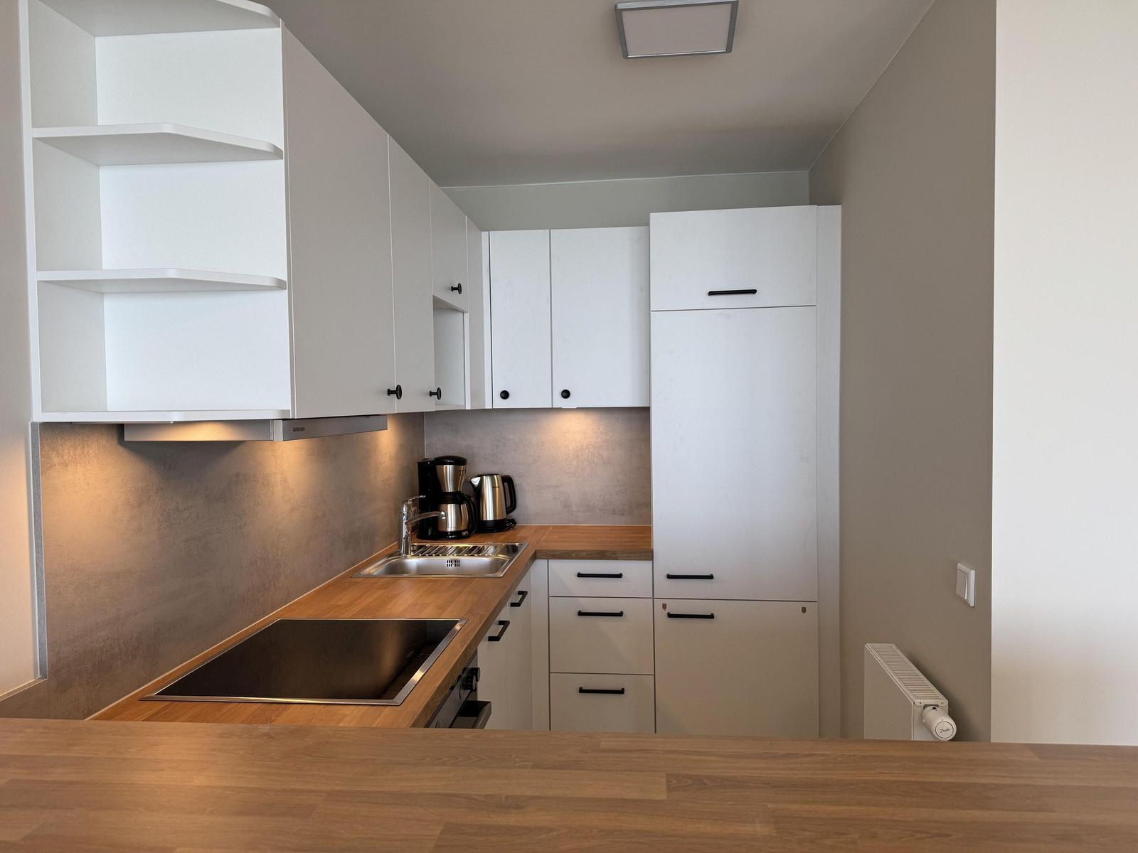 Modern kitchen with white cabinets and wooden surfaces.