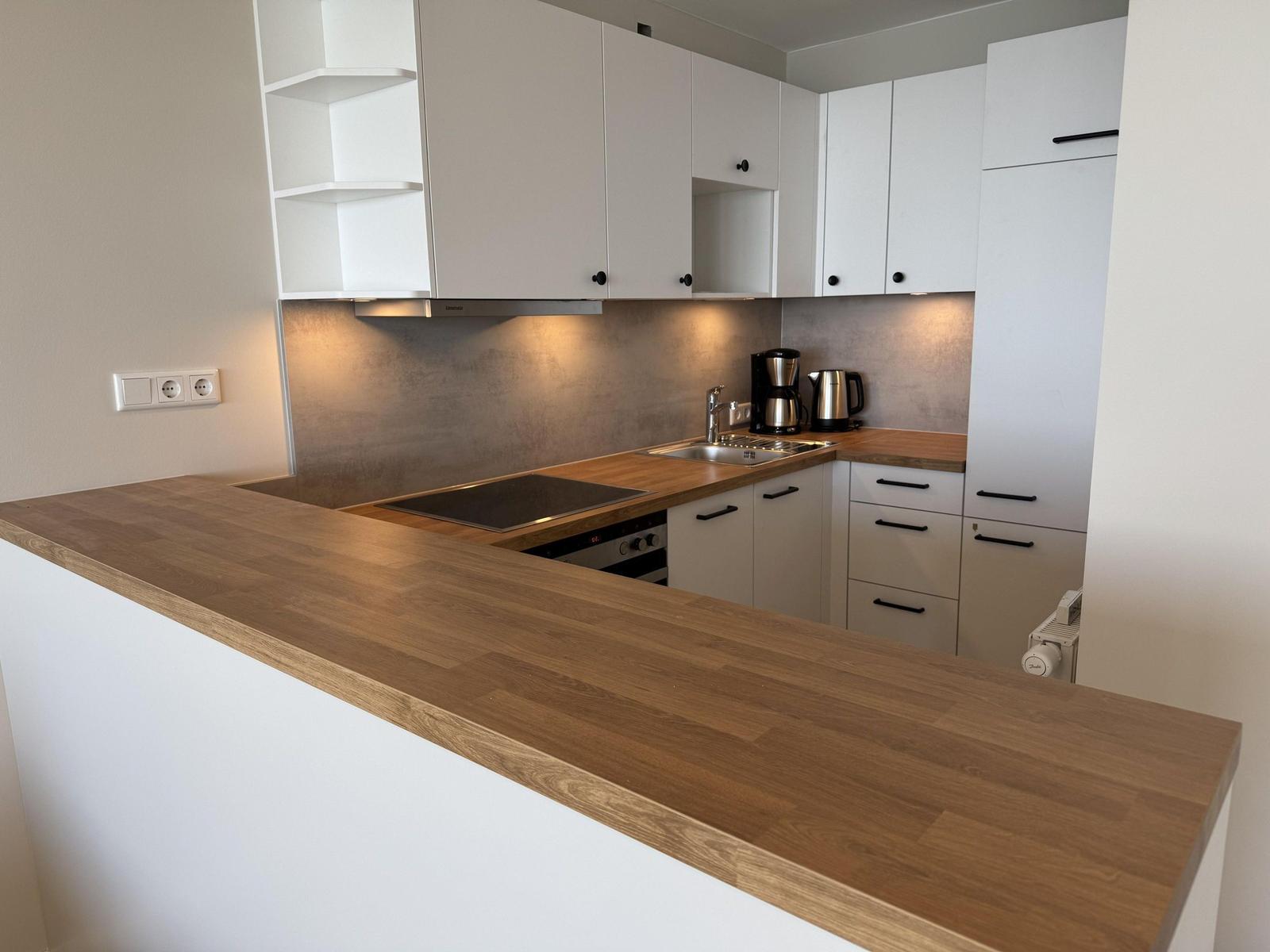 Modern kitchen with wooden countertop and white cabinets.