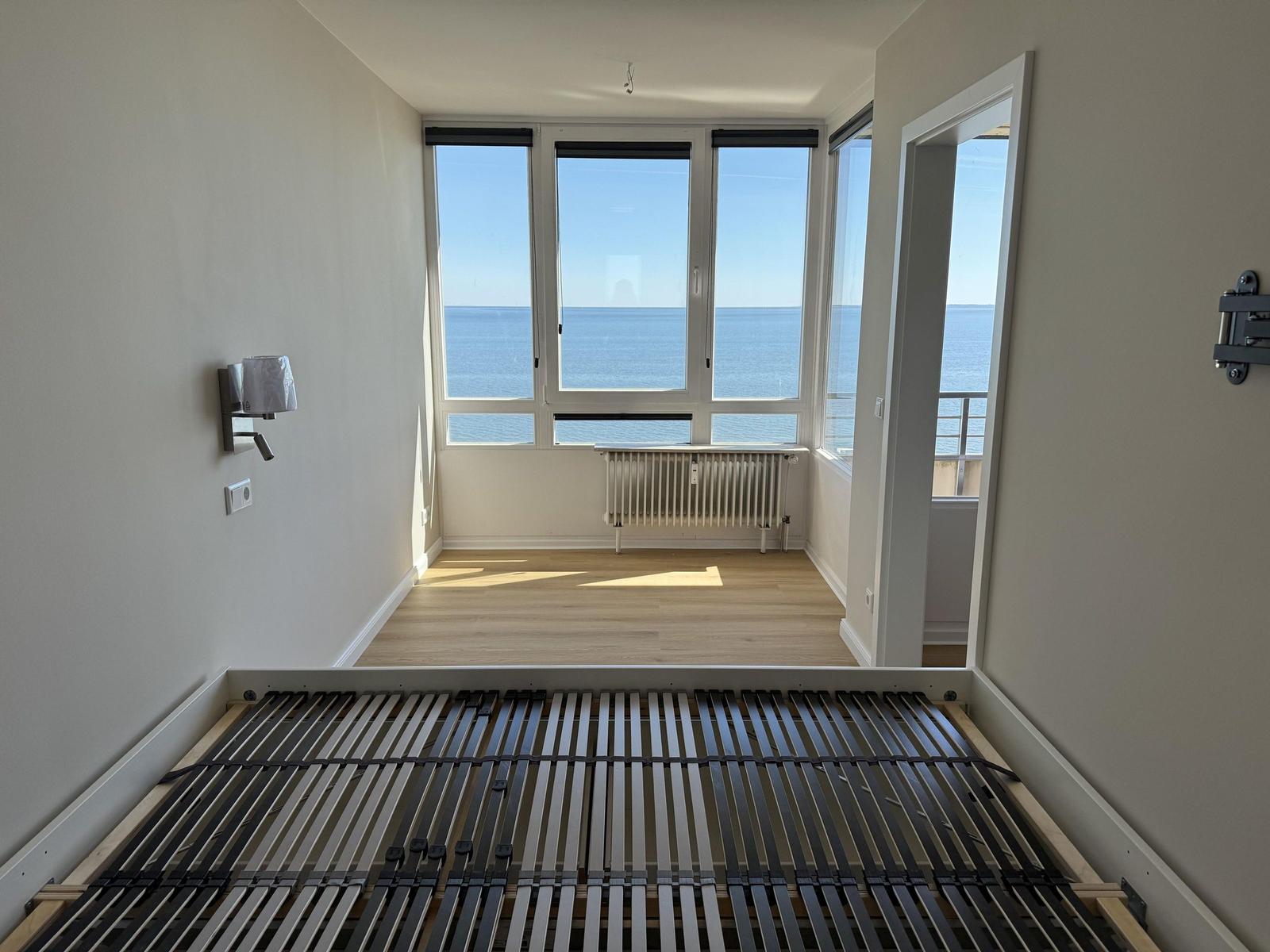 Room with sea view, wooden floor, and bed frame