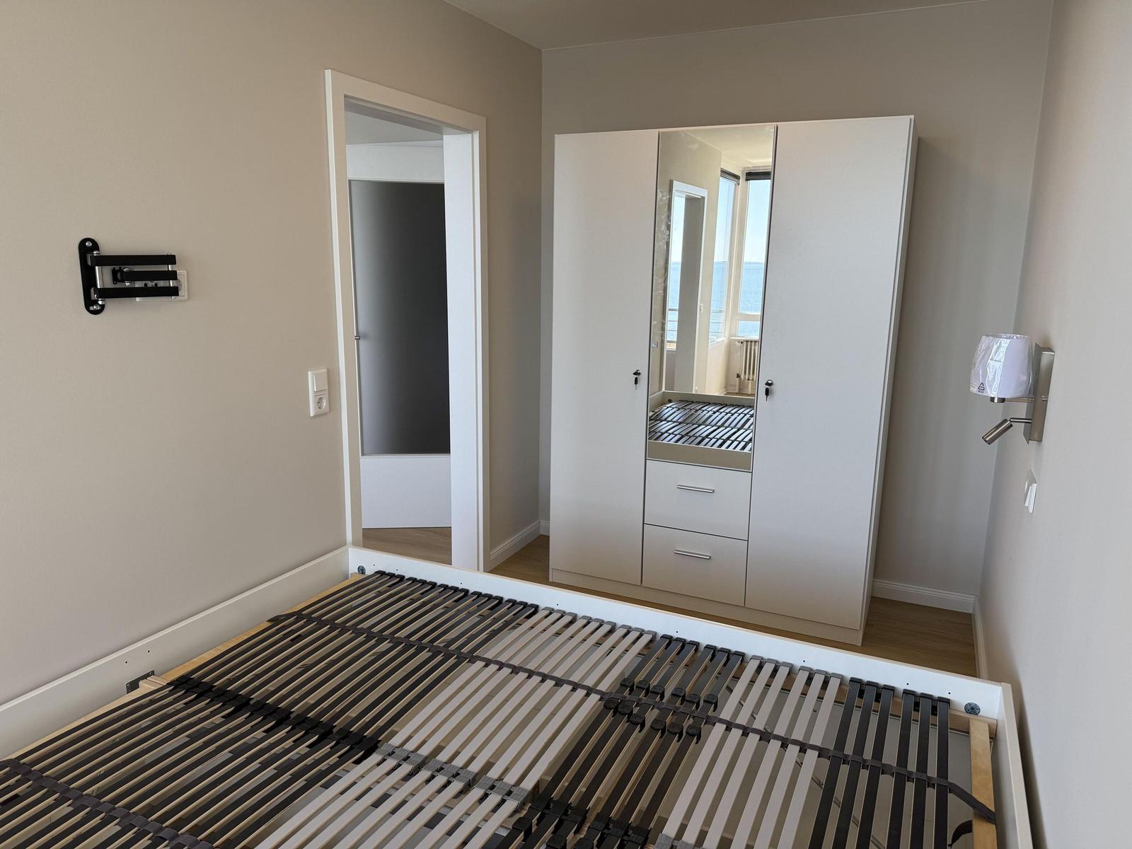 Bedroom with bed frame, wardrobe, and door to bathroom.