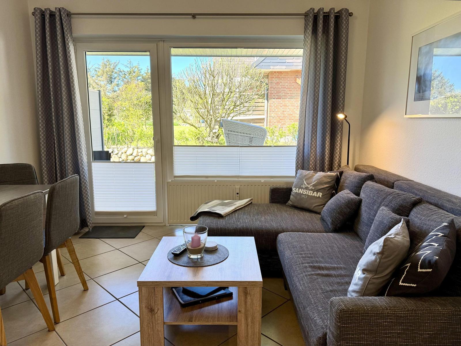 Wohnzimmer mit Sofa, Couchtisch und Fenster zum Garten