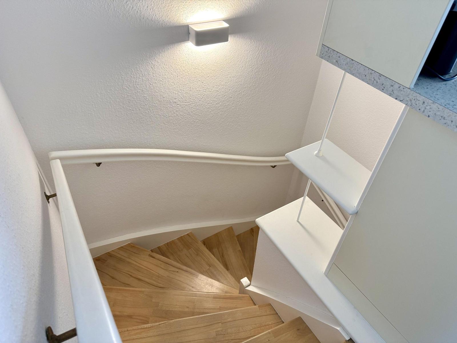 Helle Treppe mit Holzstufen und weißer Handlauf