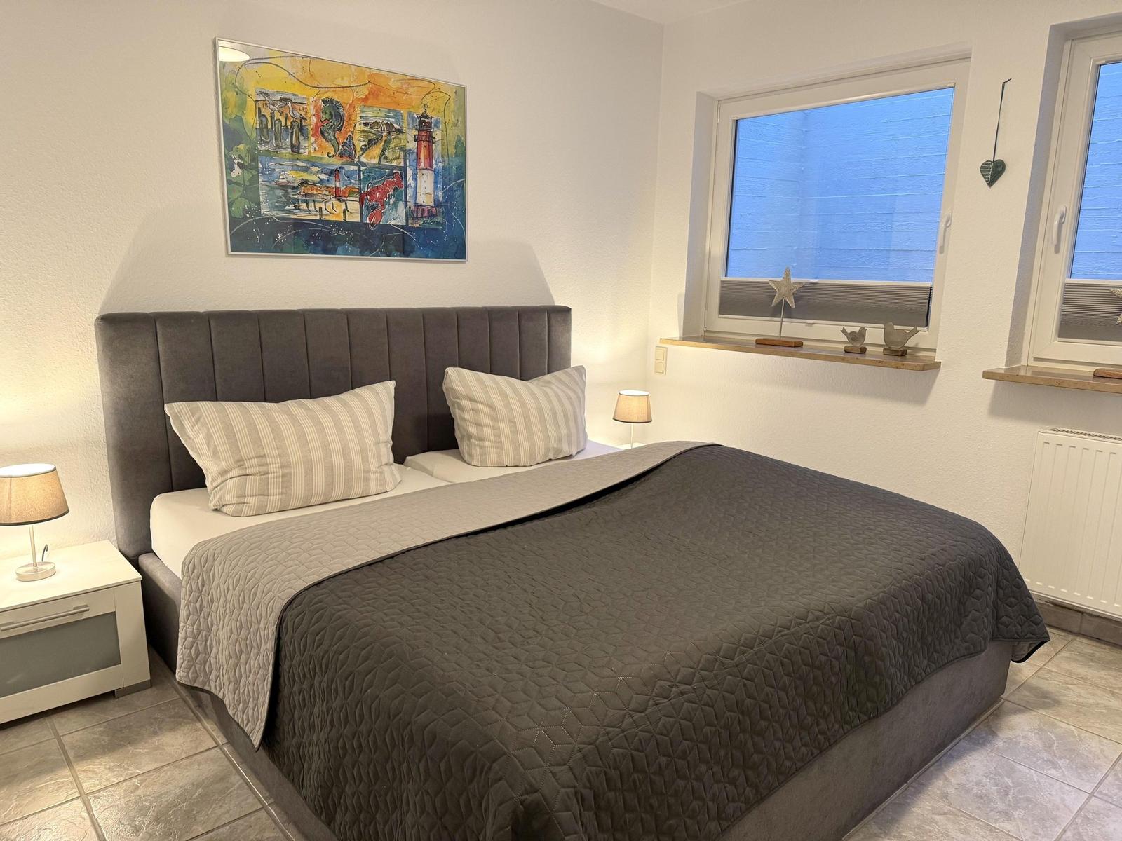 Schlafzimmer mit Bett, Nachttischen und Fenster