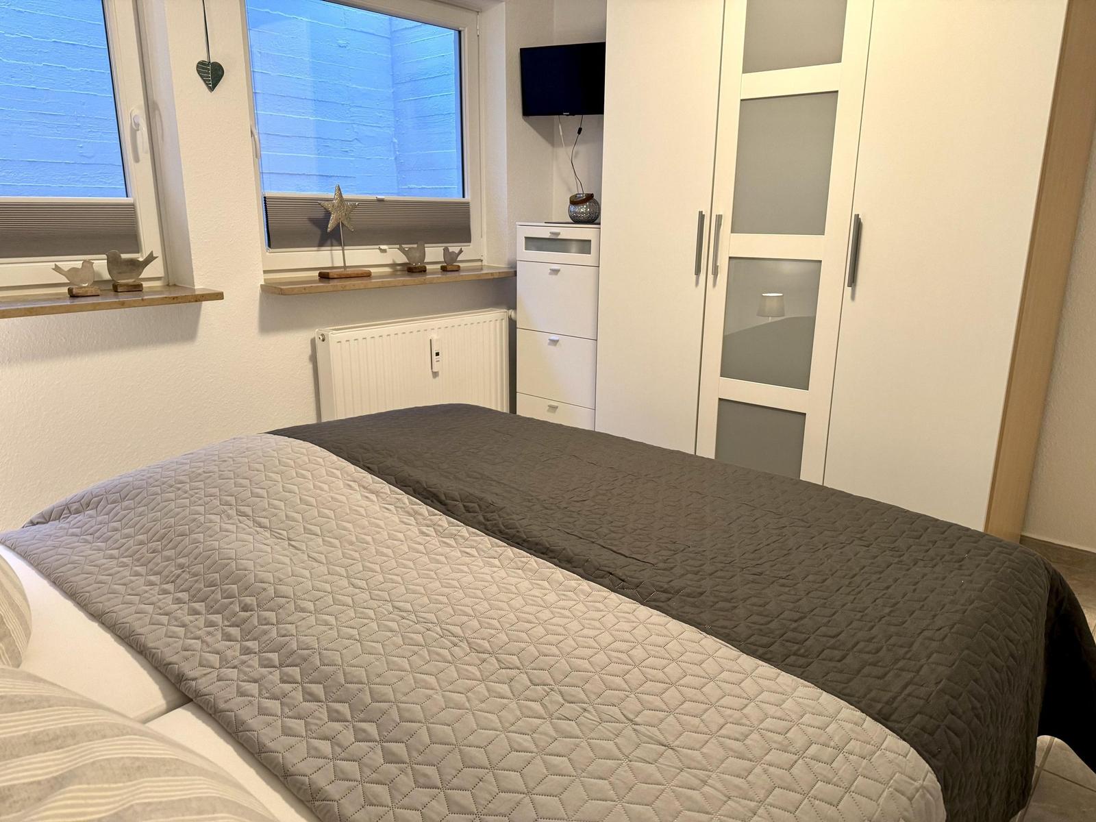 Schlafzimmer mit Bett, Kleiderschrank und Fenster