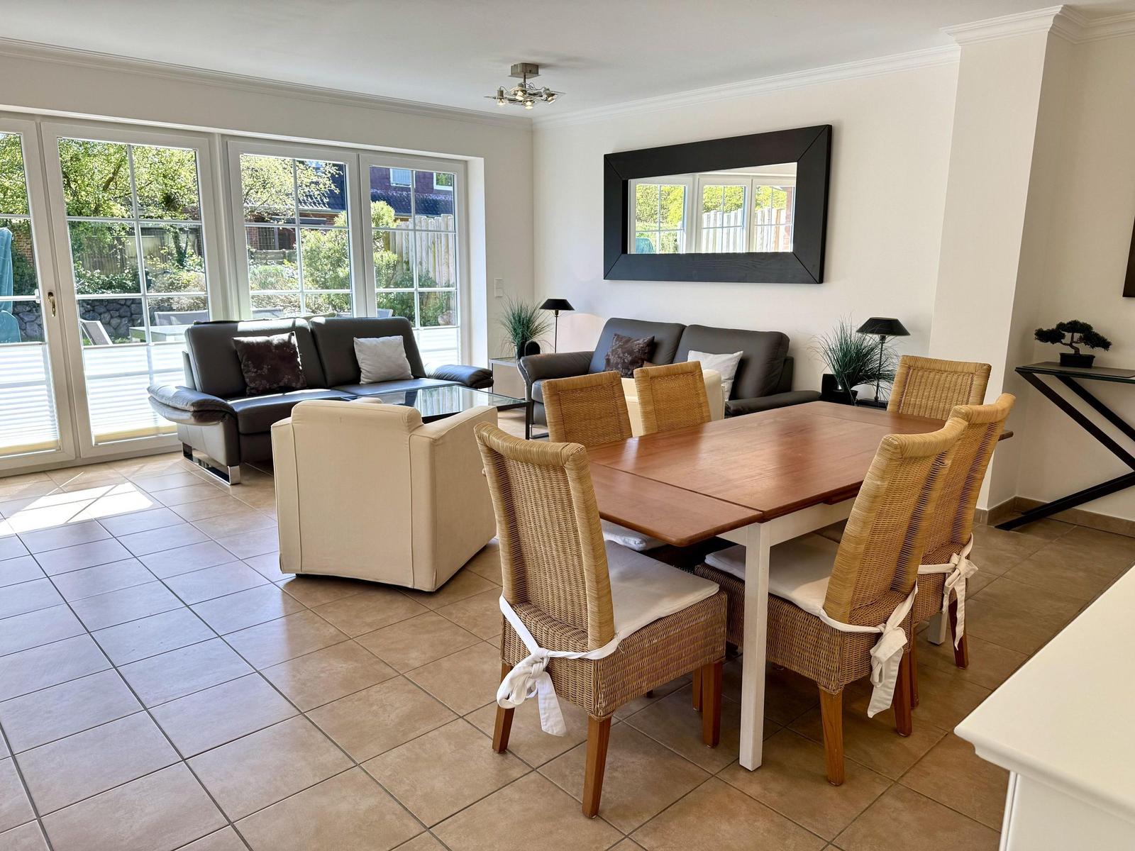 Essbereich mit Holztisch und Stühlen, Wohnbereich mit Sofa und Fenster zur Terrasse.