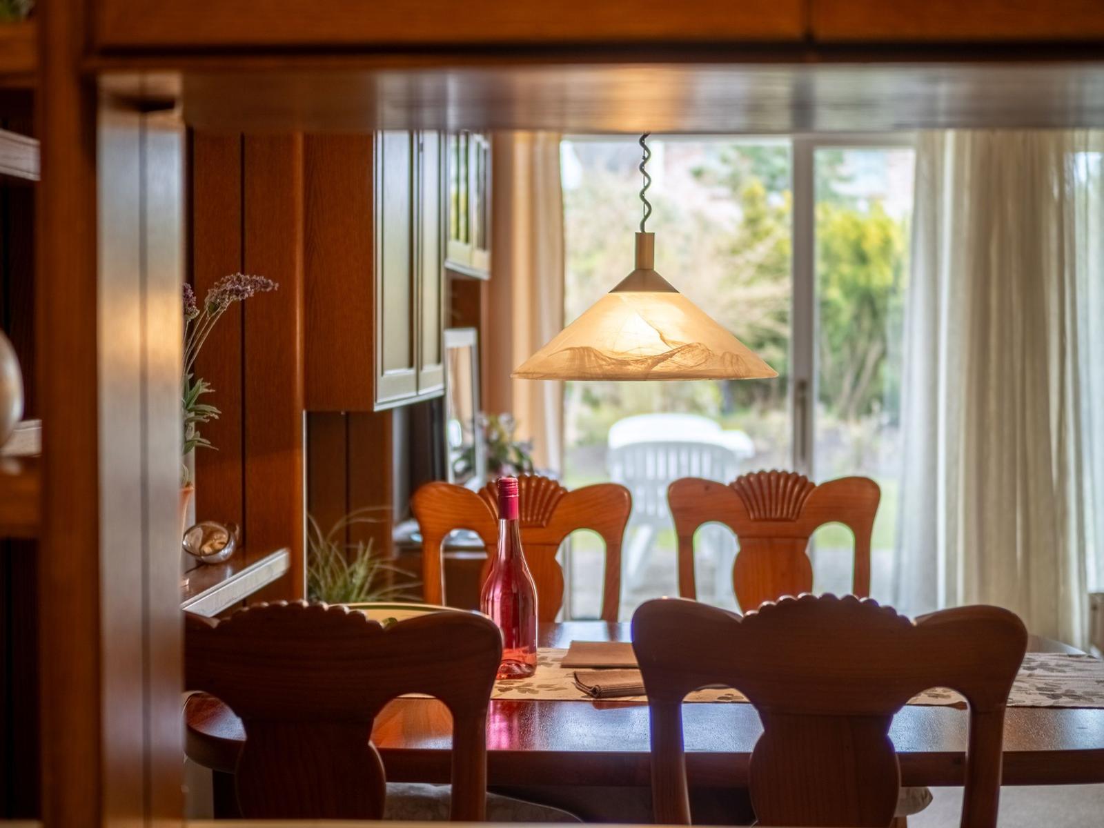 Esszimmer mit Holztisch, Stühlen und Fensterblick auf Garten