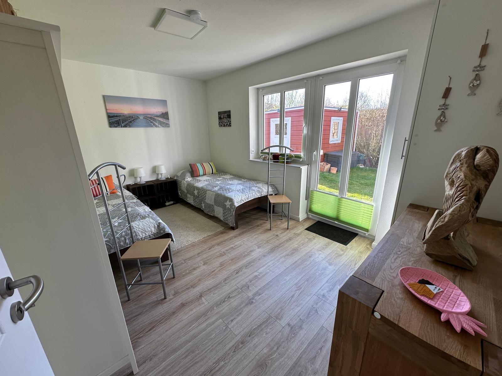 Zwei Betten, Fenster mit Blick auf Garten, Holzboden und Kleiderschrank