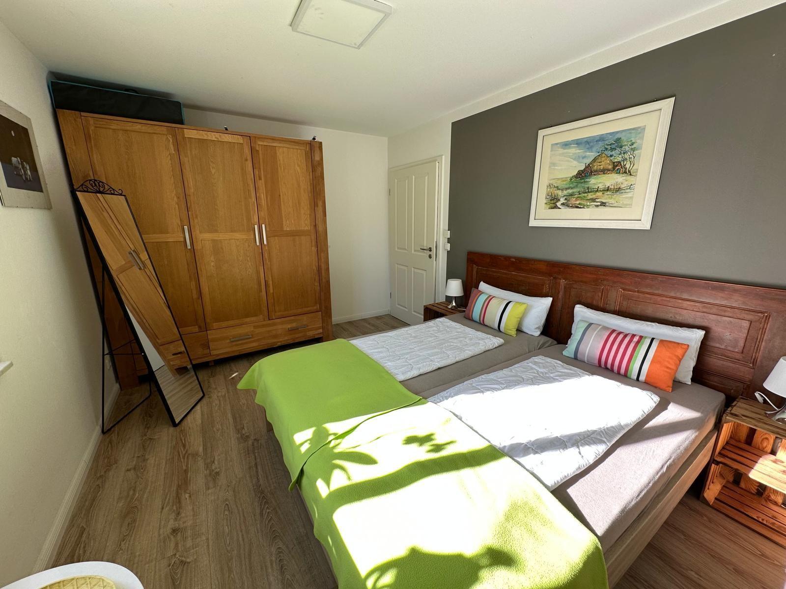Schlafzimmer mit Doppelbett, Holzmöbel und Wandbild.