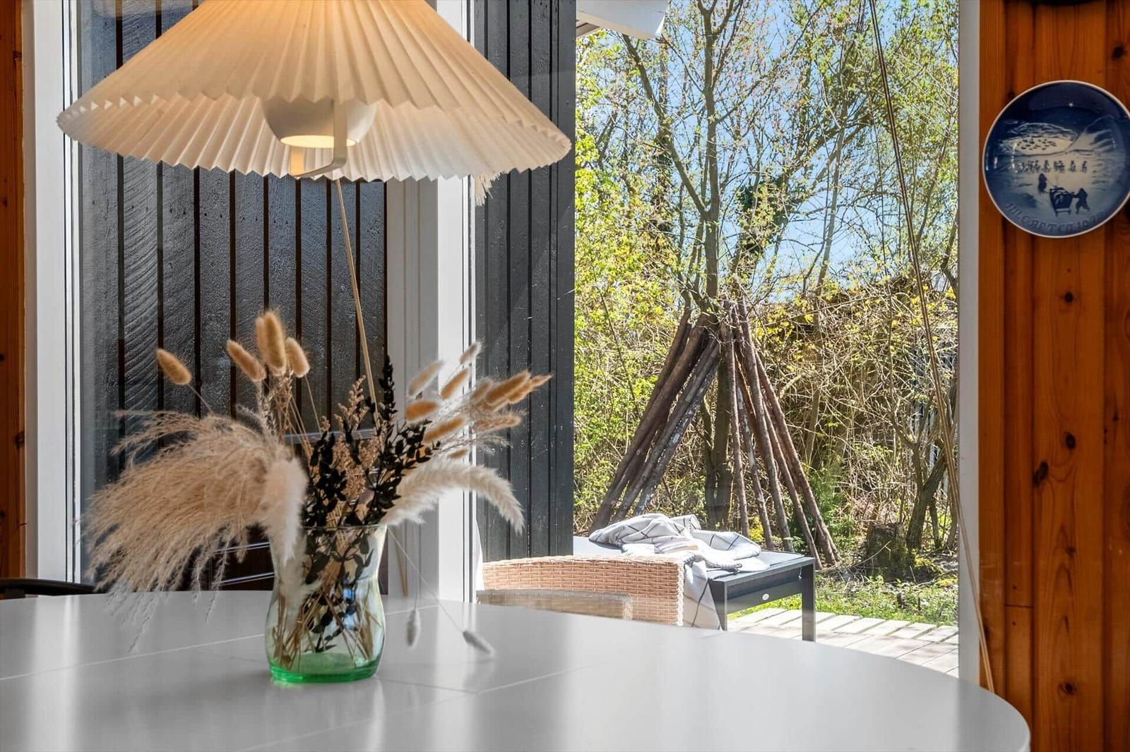 Table with vase flowers and view of wooden garden with lounger.