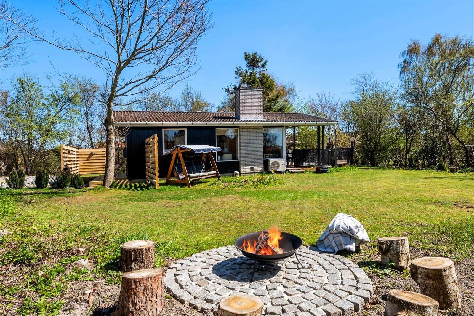 House with garden, fire pit, and tree stumps as seating.