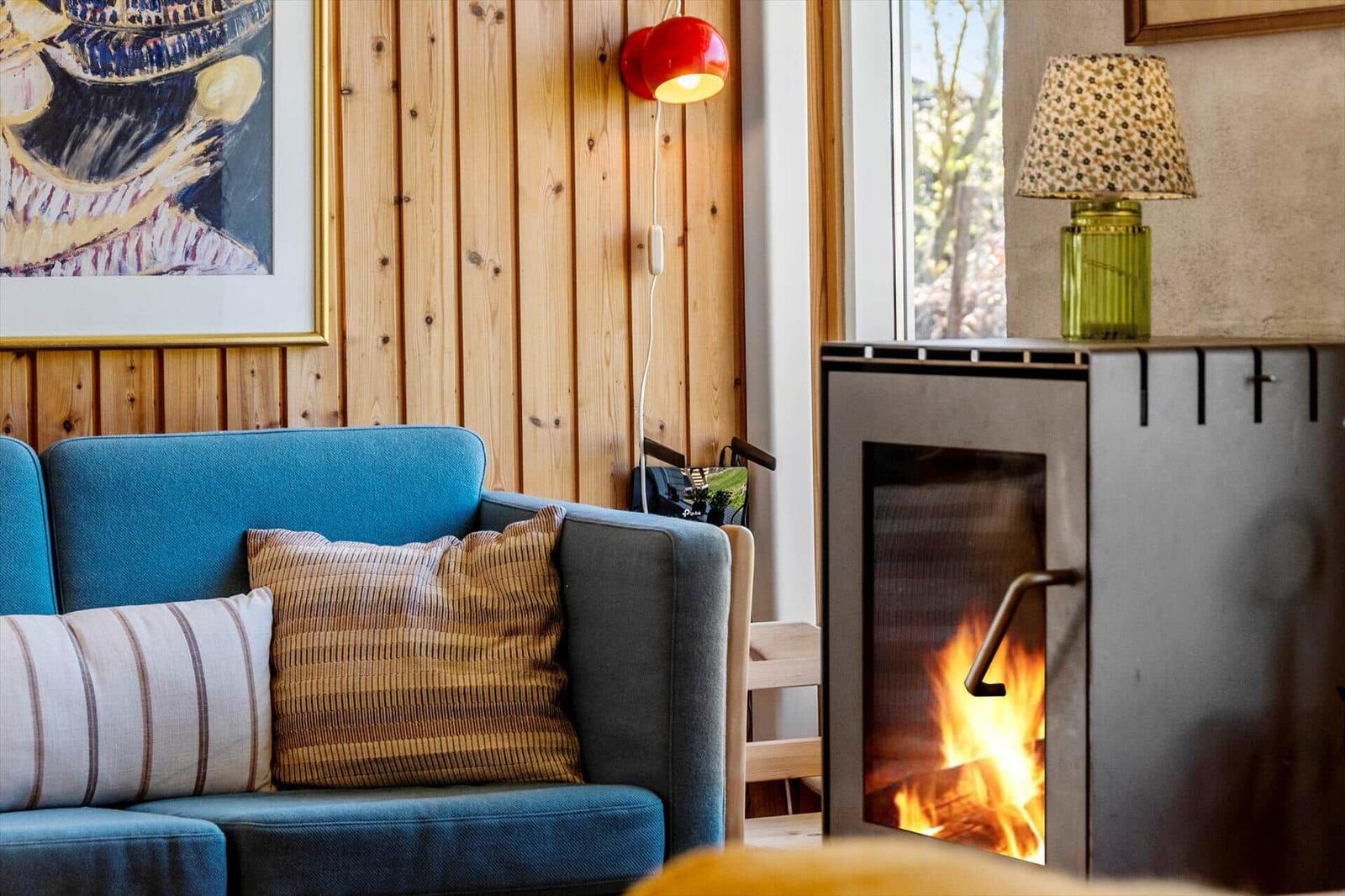 Blue sofa with cushions, fireplace, and wooden wall in living area.