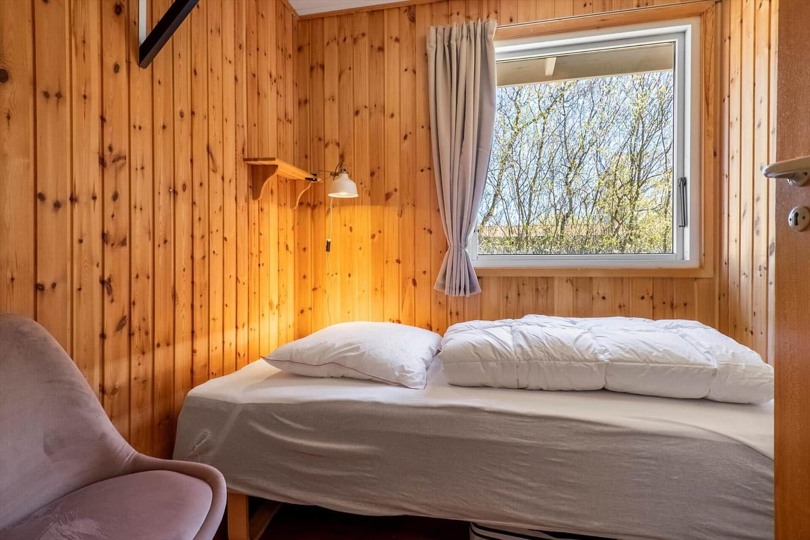 Bedroom with bed, window, and wooden wall