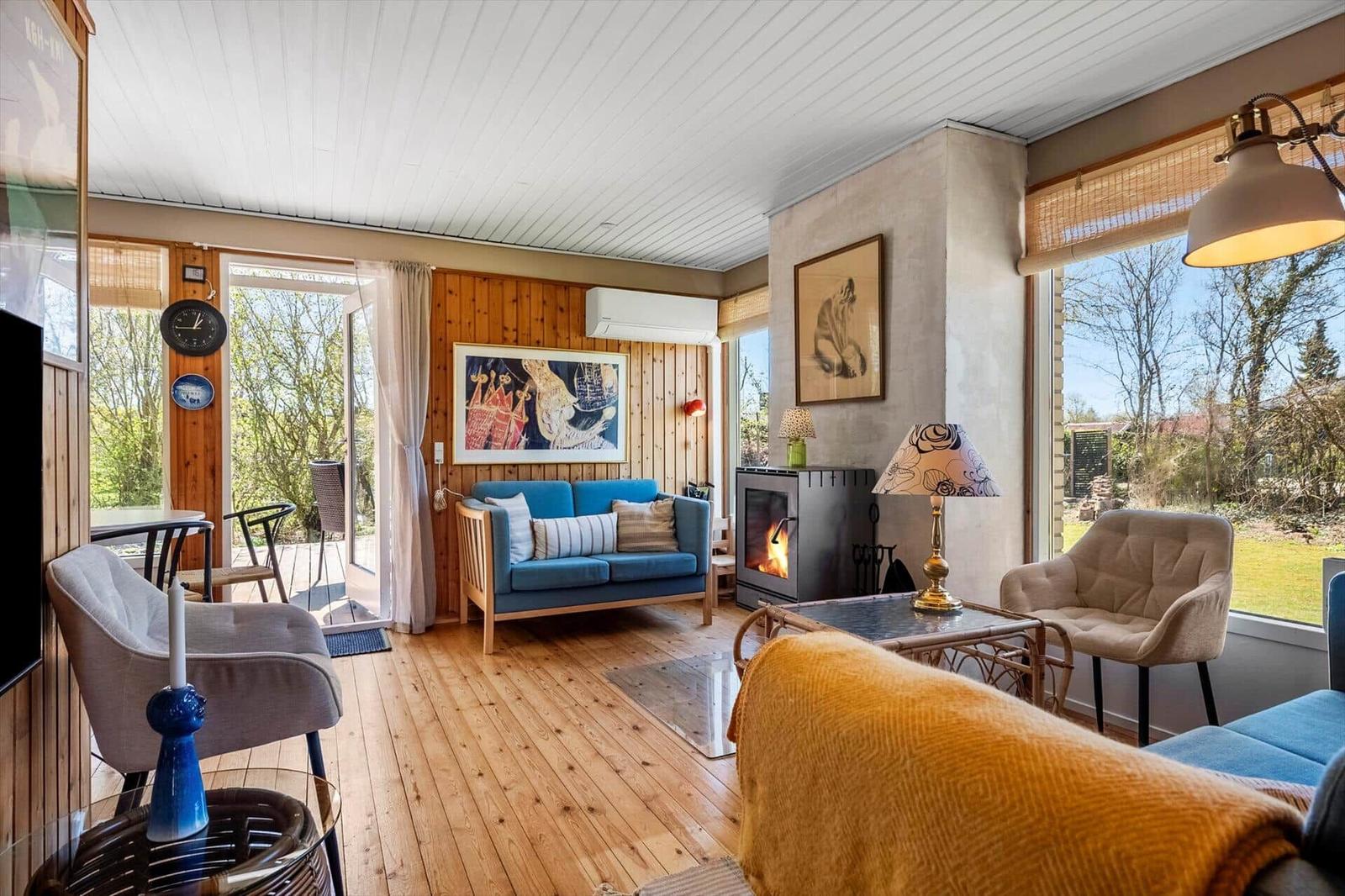 Living room with fireplace, sofa and armchairs. Wooden floor and large windows.
